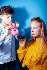happy family brother and sister eating donuts on blue background, lifestyle people concept, boy and girl eating unhealthy food