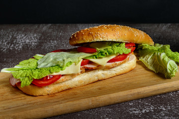 Homemade sandwich with ham, cheese, bacon, tomatoes and salad 