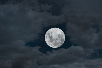 Naklejka na ściany i meble Full moon between clouds in the night.