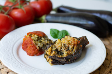 Traditional Azerbaijani eggplant dolma also called three sisters made vegan: an aubergine and a tomato stuffed with spicy rice and basil instead of the minced beef in a white plate