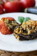 Traditional Azerbaijani eggplant dolma also called three sisters made vegan: an aubergine and a tomato stuffed with spicy rice and basil instead of the minced beef in a white plate
