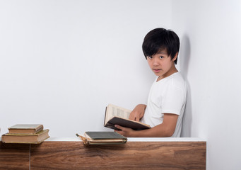 Young Asian boy reading book in library