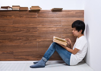 Young Asian boy reading book in library