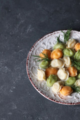 Dish with multi-colored dumplings on a dark rustic background.
