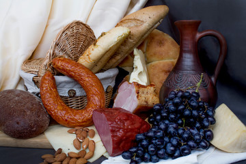 Still-life. Wine. Glass of wine. Cheese. Sausage. Bread. Basket. Grape. A decanter of wine. Nuts almonds