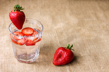 A refreshing drink of strawberries in a glass and berries on a background of a napkin made of...