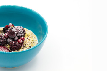 Oatmeal with blueberries and sugar in blue glass bowl isolated on white background. Cereals. Healthy breakfast. good digestion. Space for text.
