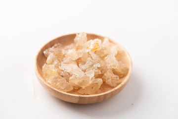 Fresh peach gum in a wooden bowl against a white background