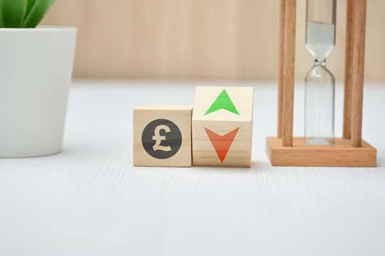 Wooden blocks with GBP pound sterling sign and up and down arrows.