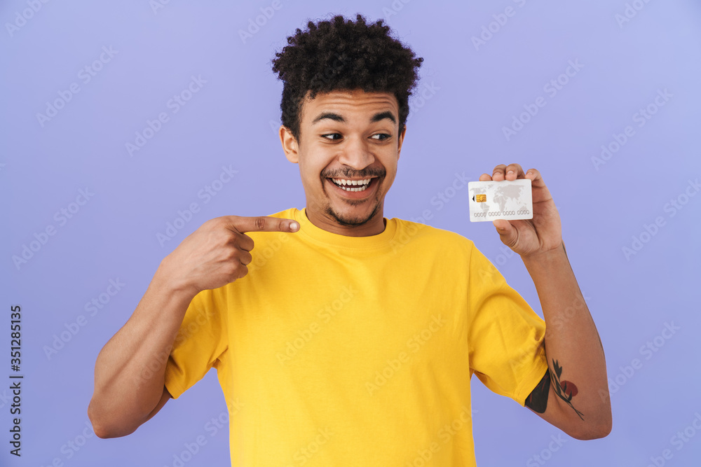 Wall mural Photo of african american man holding and pointing finger at credit card