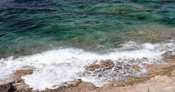 Sea waves break about the rocky coas, the cape Ferrat of South France, embankment on the azure coast, mountains and the blue sky on background, 