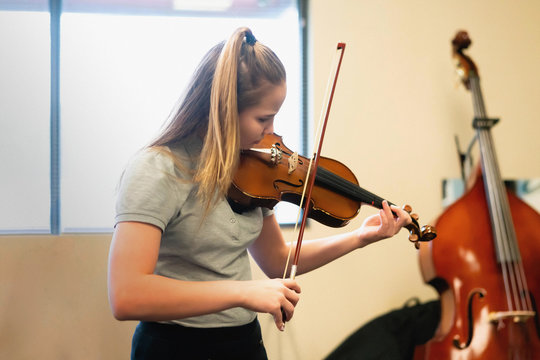 Teenage girl playing violin in classroom