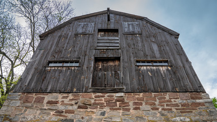 Fototapeta na wymiar Looking up at an old wooded barn built on a huge stone foundation. Perspective image of vintage New England farm building 