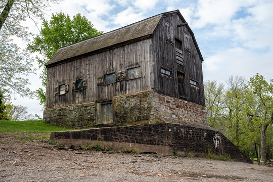 Looking up at an old wooded barn built on a huge stone foundation. Perspective image of vintage New England farm building 