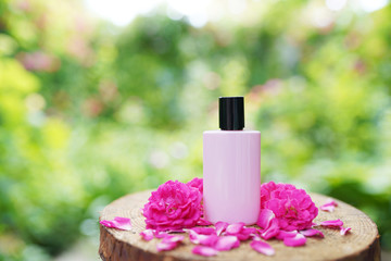 Obraz na płótnie Canvas Elegant woman perfume bottle with pink flowers on wood