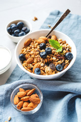 Baked granola with yogurt and blueberries on a gray table.
