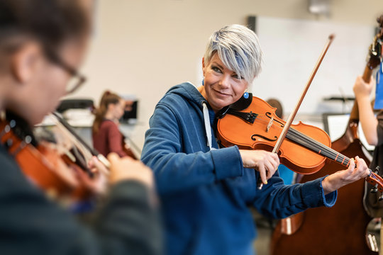 Teacher teaching student to play violin in classroom