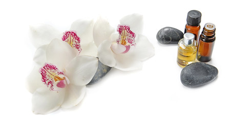 Obraz na płótnie Canvas oil bottles and pebbles with beautiful orchids on white background