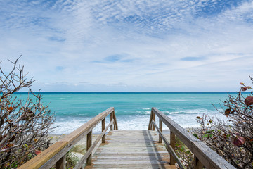 Fototapeta na wymiar Wooden Walkway Leading Down to a Picturesque Turquoise Ocean