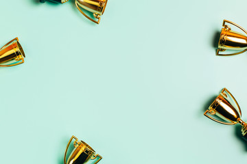 Frame made of winner cups on a pastel blue background with copy space. Flat lay style.