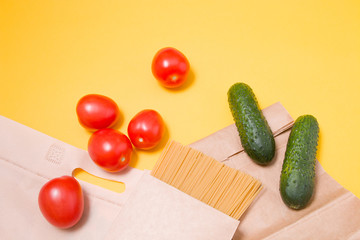 fabric eco bag with products on a yellow background, tomatoes, spaghetti in a cardboard box, paper bag and cucumbers top view, no plastic bag concept, zero waste life style