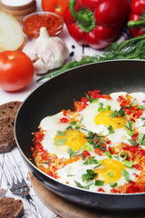 Shakshouka with five cooked eggs on top of tomato sauce in cast iron skillet