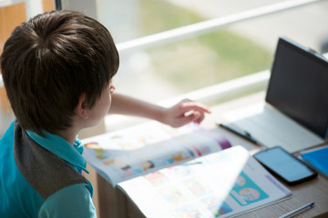 Nine years old child studying  and doing school homework. Distance learning online education or stay at home concept. Soft focus.