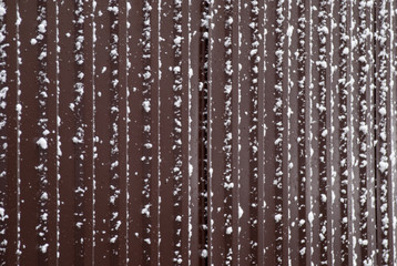 Naklejka na ściany i meble Iron brown fence covered with snow.