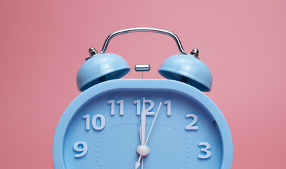 Closeup Blue Alam clock Twelve o'clock on pink background, Time concept.