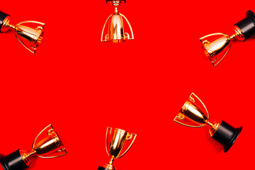 Winner cups on a red background with copy space. Flat lay style.