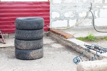 Four used car tires stacked on top of each other near the tire shop. Replacing the wheel on the...