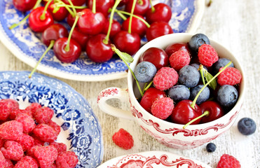 Red and blue berries - forest blueberries, blueberries, raspberries, cherries in a  dish with a red and blue pattern.  Summer berries. Soft focus
