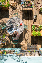 Top view, a woman is working on her laptop on a table, on her flowered terrace