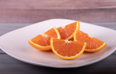 Fototapeta na wymiar Slices orange fresh juicy oranges on white dish, wood background.
