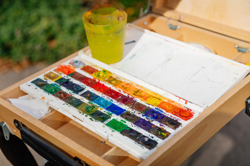 Watercolor palette in white box on wood easel