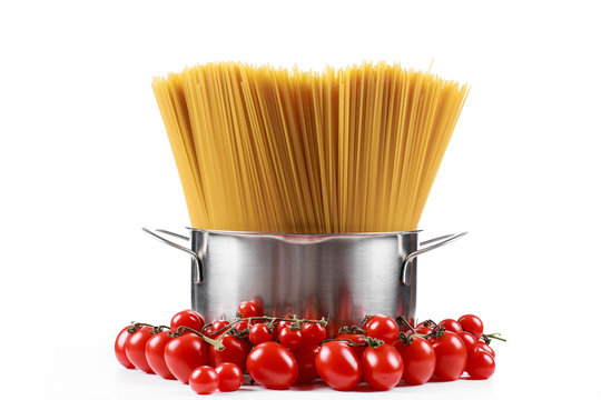 Pasta spaghetti in a metal pan in a large collum on a white background with tomatoes.