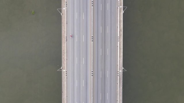 Aerial drone view of the bridge across the river with moving cars.