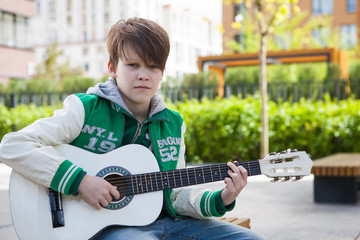 Cute little boy is playing guitar in the park.