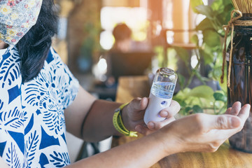 Woman using alcohol nano mist sprayer antiseptic cleaning on her hands protection during...