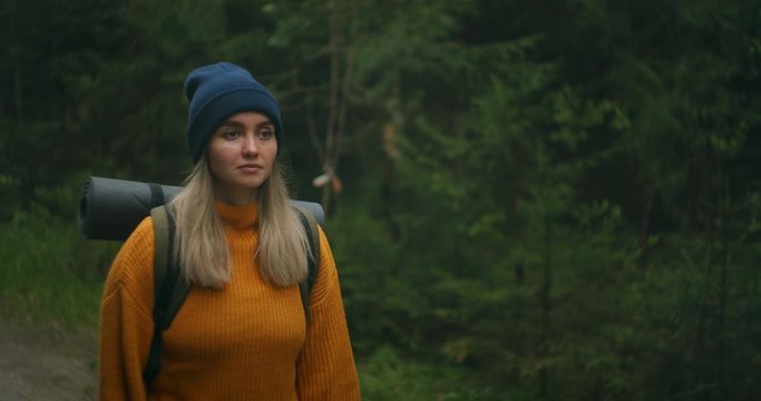 Slow motion female hiker walks along levada trail in forest. Happy female backpacker admiring nature walking on countryside road. Woman tourist walking in the fall forest on sunny autumn day.