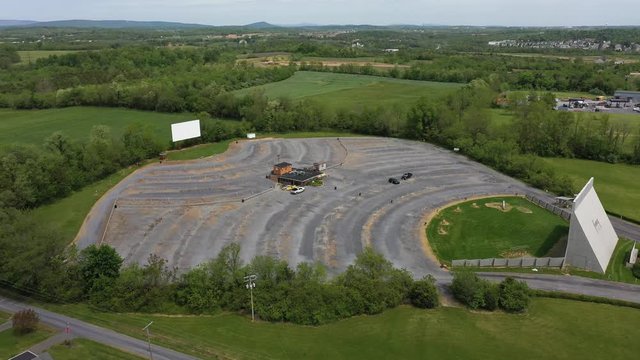 Aerial push in to a two screen drive-in movie theater with the camera tilting down at the end.