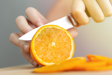 Close up hands cutting a ripe juicy orange with a knife. Healthy fruit food preparation concept 