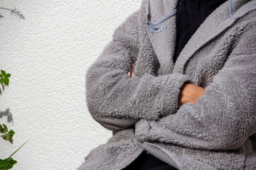 Fototapeta na wymiar Person with folded arms and a gray hairy dressing gown