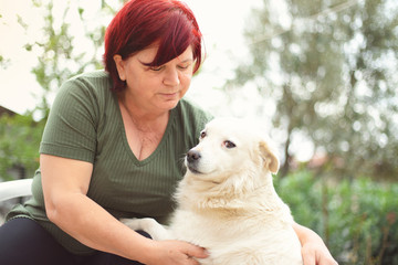 mature woman spends pleasant time in the garden of her house with her cute dog.