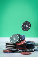 Poker playing chips on a wooden table and green background. Online gambling. Addiction. Falling poker chips