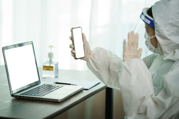 Woman in protective hazmat suit worker  in laboratory computer resting and video calling on smart phone. to stop spreading  coronavirus or COVID-19.