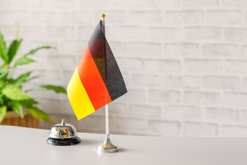 Silver vintage bell with national flag of Germany on reception desk with copy space. Hotel service....
