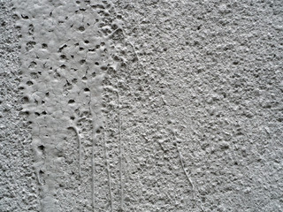 Old gray stucco with smudges of paint. The paint is cracked. Stone background with whitewash and smudges of paint.