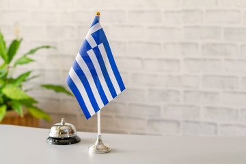 Silver vintage bell with national flag of Greece on reception desk with copy space. Hotel service....