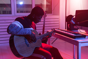 Obraz premium Create music and a recording studio concept - African american man guitarist recording electric guitar track in home studio